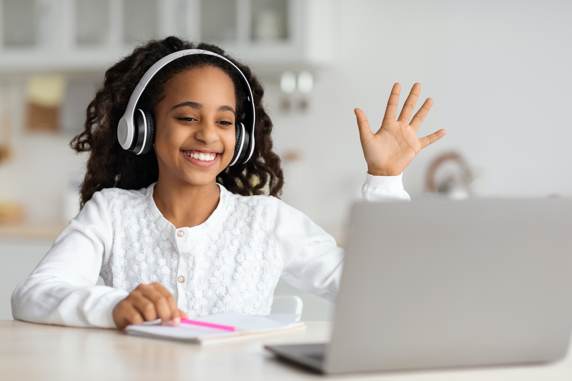 Positive african american kid waving at laptop screen